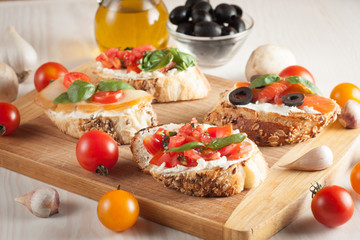 Italian tomato and cheese bruschetta. Tapas, antipasti with chopped vegetables, herbs and oil on grilled ciabatta and baguette bread.