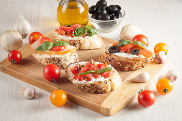 Italian tomato and cheese bruschetta. Tapas, antipasti with chopped vegetables, herbs and oil on grilled ciabatta and baguette bread.