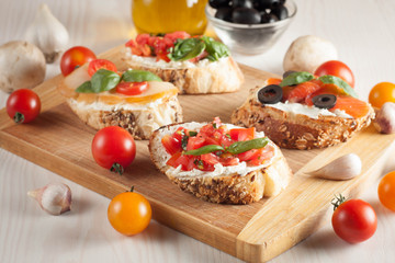 Italian tomato and cheese bruschetta. Tapas, antipasti with chopped vegetables, herbs and oil on grilled ciabatta and baguette bread.
