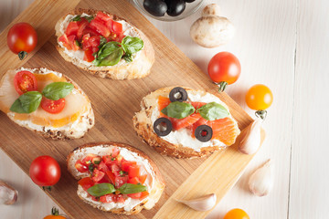 Italian tomato and cheese bruschetta. Tapas, antipasti with chopped vegetables, herbs and oil on grilled ciabatta and baguette bread.