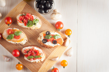 Italian tomato and cheese bruschetta. Tapas, antipasti with chopped vegetables, herbs and oil on grilled ciabatta and baguette bread.