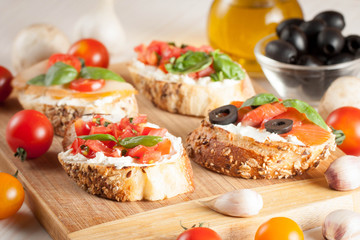 Italian tomato and cheese bruschetta. Tapas, antipasti with chopped vegetables, herbs and oil on grilled ciabatta and baguette bread.