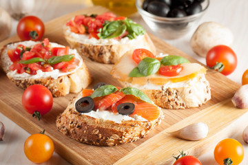 Italian tomato and cheese bruschetta. Tapas, antipasti with chopped vegetables, herbs and oil on grilled ciabatta and baguette bread.