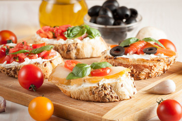 Italian tomato and cheese bruschetta. Tapas, antipasti with chopped vegetables, herbs and oil on grilled ciabatta and baguette bread.