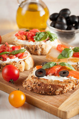 Italian tomato and cheese bruschetta. Tapas, antipasti with chopped vegetables, herbs and oil on grilled ciabatta and baguette bread.