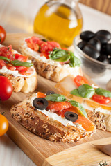 Italian tomato and cheese bruschetta. Tapas, antipasti with chopped vegetables, herbs and oil on grilled ciabatta and baguette bread.