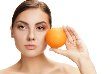 The portrait of attractive caucasian smiling woman isolated on white studio background with orange fruit. The beauty, care, skin, treatment, health, spa, cosmetic and advertising concept