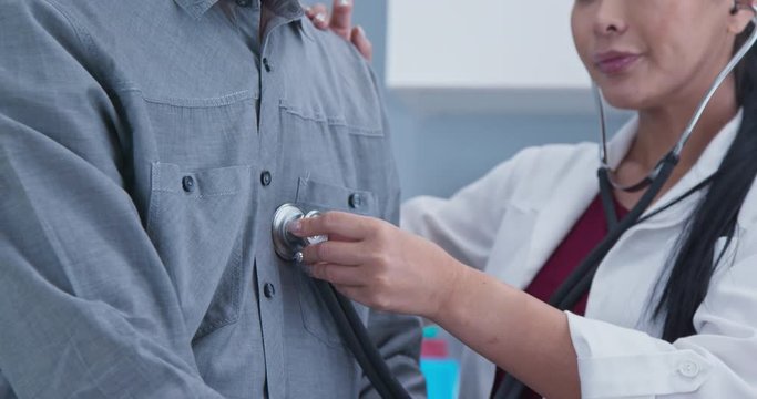 Close up on doctor using stethoscope to listen to breathing and heart rate
