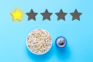 Bowl of popcorn and can with drink on a blue background. Added one star rating. Reputation. Concept of watching movies, TV shows, sports. Audit and evaluation. Flat lay, top view.