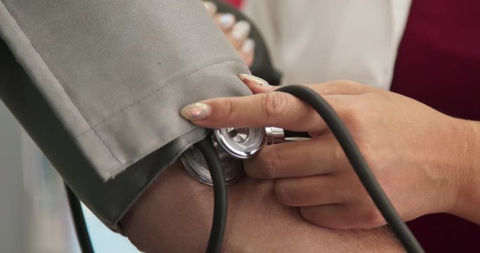 Extreme close up on doctor using sphygmomanometer to check blood pressure - Powered by Adobe