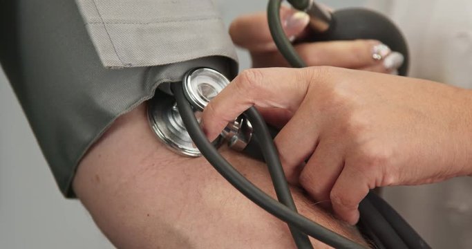 Close up on doctor using sphygmomanometer to check patient blood pressure