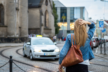 Tourist woman waiting for taxi car on the street in old city