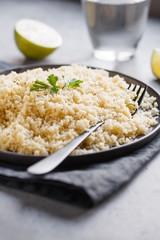 Couscous on a black ceramic plate on a table. The concept of vegetarian and healthy food.