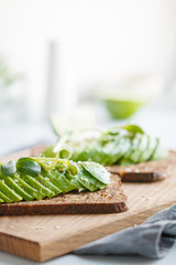 Toasts with avocado on a wooden tray on a table. The concept of vegetarian and healthy diet food.