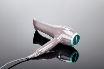 Brown hair dryer with concentrator on the grey mirror background and copy space.
