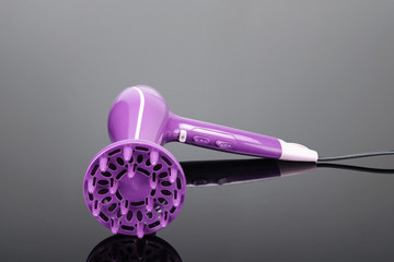 Pink hair dryer with diffuser on the grey mirror background with copy space
