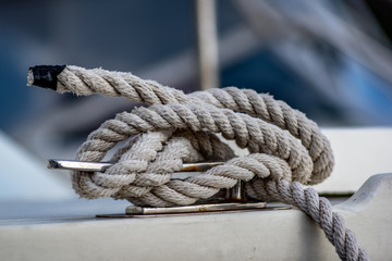 Fototapeta na wymiar Close up view of white rope tied around ship bollard.