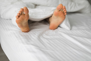 Male foots in a bed