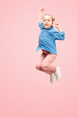 Young happy caucasian teen girl jumping in the air, isolated on pink studio background. Beautiful...