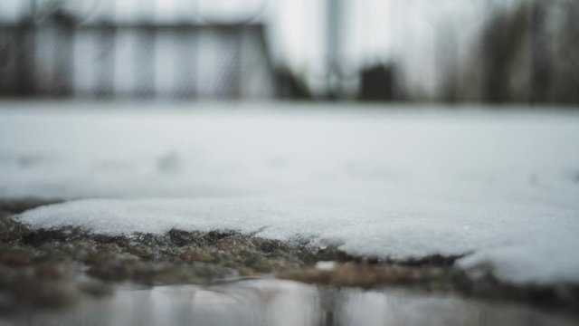 melting snow on a winter tga. The stone plates covering a terrace is thinly covered with wet snow. the dew water spans the surface