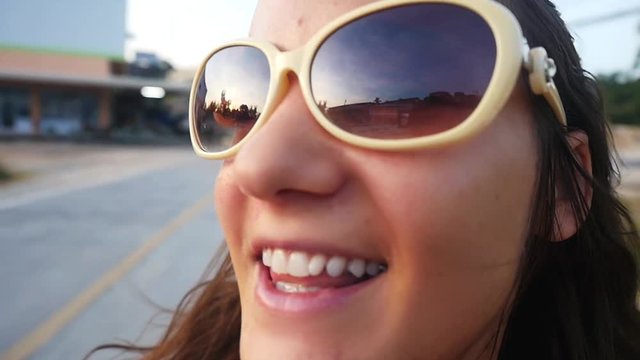 Young happy woman in sunglasses rides on motorbike on road of tropical island. slow motion. Close up of her face. 1920x1080