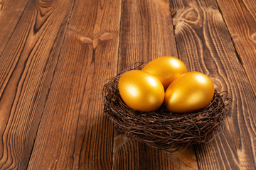 gold eggs on a nest on wooden background