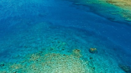 stunning aerial drone image of a great coral reef marine channel in calm weather flat water and incredible colorful sea ocean bed around a small remote isolated tropical island