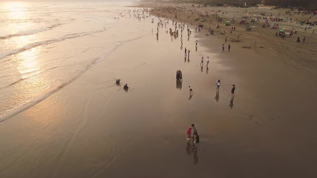 sandy beach parangtritis near ocean with big waves, people in tropical resort at sunset. Yogyakarta, Indonesia. aerial view seascape, ocean and beautiful beach. Travel concept. Indonesia, java