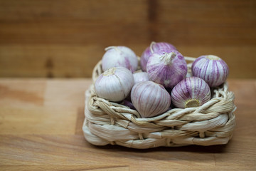 garlic in wicker basket on wooden background