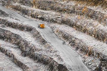 Large orange mining truck in a quarry. Iron ore extraction. Heavy mining equipment. View from above on opencast mining quarry for the extraction of ironstone magnetite ores 