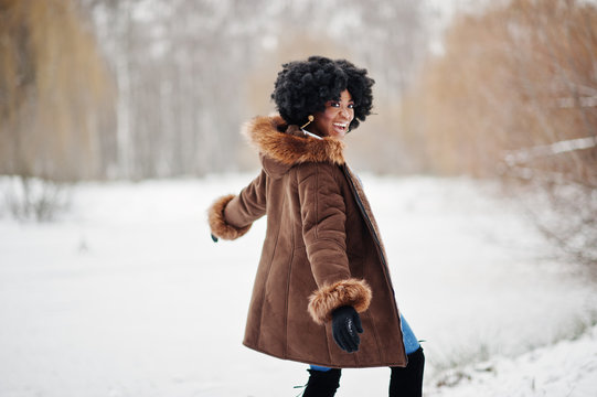 Curly hair african american woman wear on sheepskin coat and gloves posed at winter day.