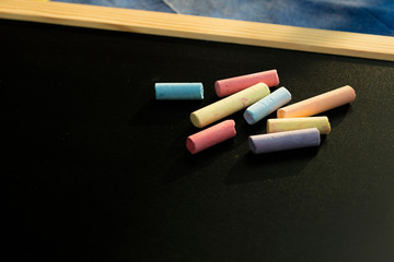 Group of multicolored chalks on black chalkboard
