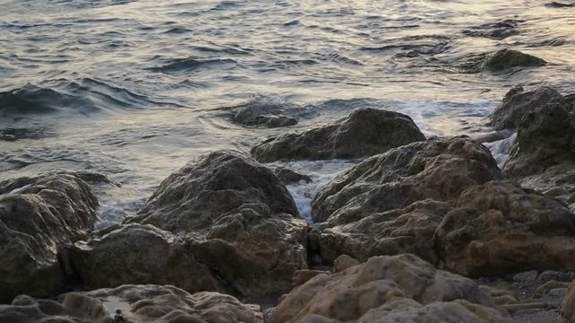 Slo-Mo - Waves at sunset beat on the rocky shore