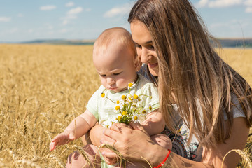 Mother with child in wheat, Young happy family in wheat field smiling and enjoying the sun