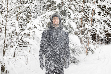 Man in fur winter hat with ear flaps smiling portrait. Extreme in the forest