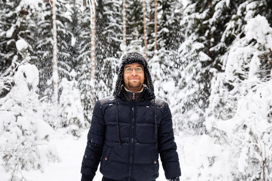 Man in fur winter hat with ear flaps smiling portrait. Extreme in the forest