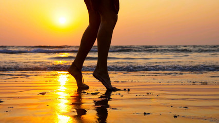 Silhouette feet of young girl dancing on the beach at sunset