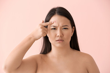 Naklejka premium Portrait of young Asian woman with acne problem on color background