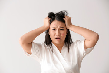 Portrait of stressed Asian woman with acne problem on white background