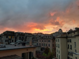 Fototapeta na wymiar Genova, Italy - 06/17/2018: An amazing sunset over the city of genova in spring days with some clouds and great reflection over the buildings