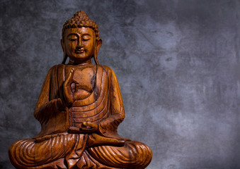 Wooden made buddha on a grey stone background