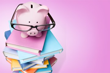 Piggy bank in glasses and books on background