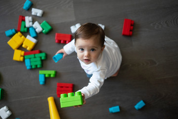 Happy baby playing with toy blocks.