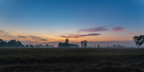 Almot sunrise at the horizon with some fog in fall season. Blue sky on top. Srisaket. Thailand