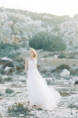 Fototapeta na wymiar Bride in the mountains with a beautiful view of Cyprus. A wedding dress and a happy girl.