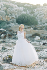 Fototapeta na wymiar Bride in the mountains with a beautiful view of Cyprus. A wedding dress and a happy girl.