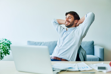 Cheerful young businessman taking break from working in home office