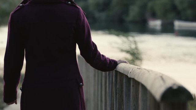 Mujer camina deslizando mano por barandilla madera embarcadero rio plano medio