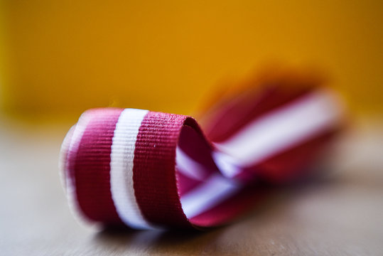 Latvia's flag ribbon on white blur background. Selective focus