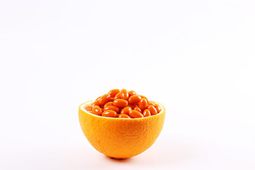 Conceptual image of vitamin c capsules in container made of orange peel. Halved citrus fruit cleaned from pulp core and filled with colorful pills. Background, copy space, close up.